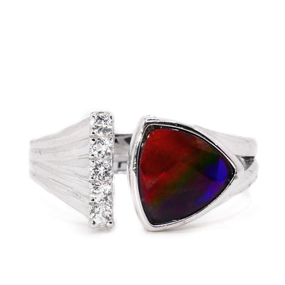 A sterling silver ring. The band is disconnected in the front. One end is wider towards the end and has white topaz details on the end. The other end has a triangular ammolite stone. The ammolite is red at the top, green in the middle, and blue in the bottom.