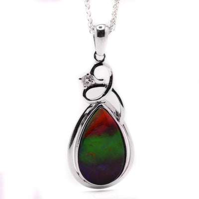 A faceted sterling silver pendant with a teardrop shaped ammolite piece embedded in the middle.