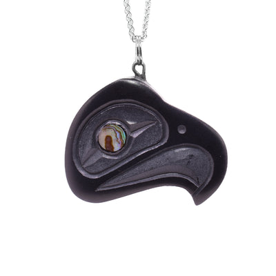 This Eagle pendant is made from black argillite and has a red argillite eye. There are carvings depicting the Eagle on the surface of the piece.