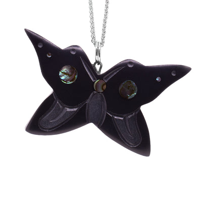 This argillite and abalone pendant is chunky and shaped like a butterfly. The piece is made of argillite and has carvings on the surface of it depicting the Butterfly. There are abalone gems set in the wings.