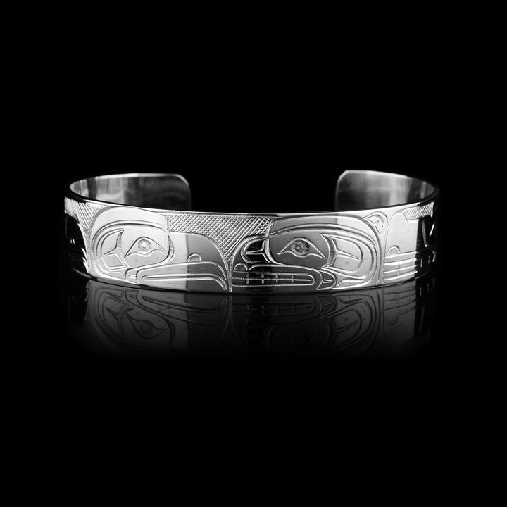 Shop this Travis Henry sterling silver cuff. Hand-carved by the Coast Salish artist, this wide silver band features a masterfully engraved Bear, Eagle, Raven, and Wolf.
