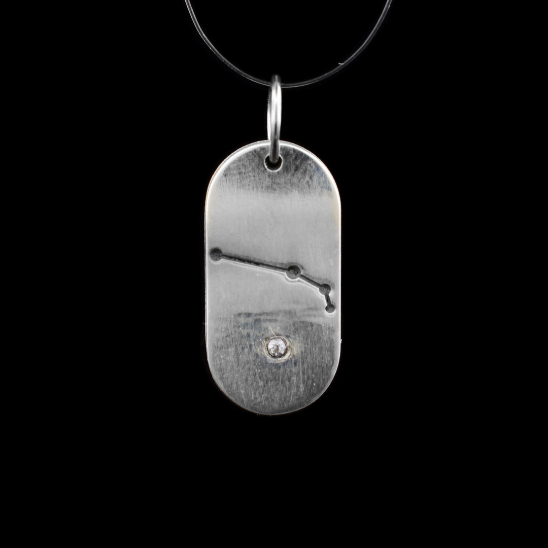 This dog tag-shaped pendant is made with sterling silver. Carved into it is the zodiac sign of Aries, representing those born in April. At the bottom, there is a cubic zirconia.