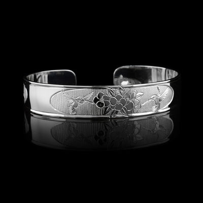 This Hummingbird with flower bracelet has a thin, sterling silver band with a gap in the back. There is a depiction of a hummingbird flying in front of rose flowers.