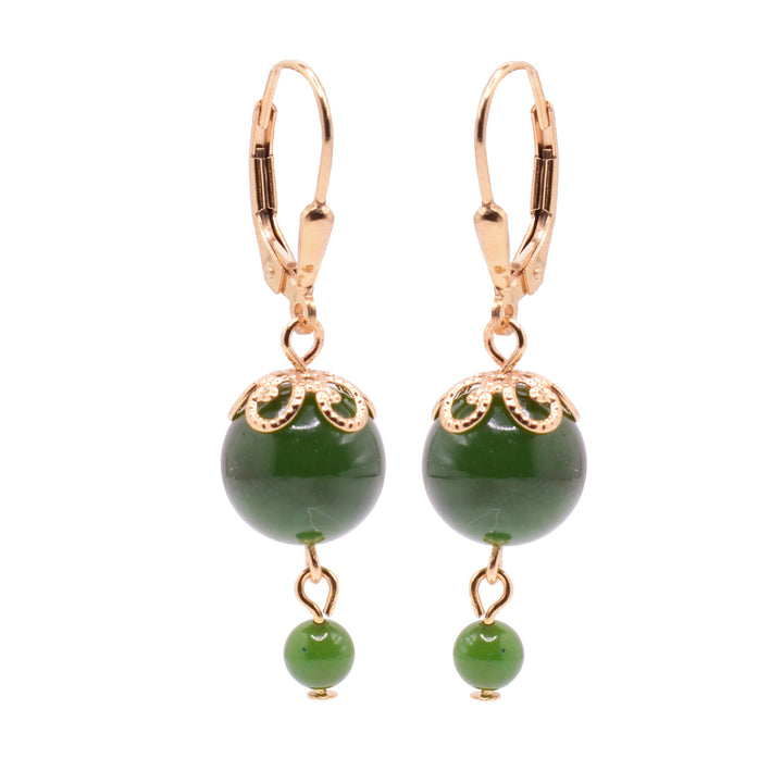 These gold jade drop earrings have large, sphere shaped jade beads dangling form gold filled, lever back hooks. There are gold designs topping the jade beads with simple, swirling designs. Below the jade beads are much smaller jade beads attached with 14K gold filled links.