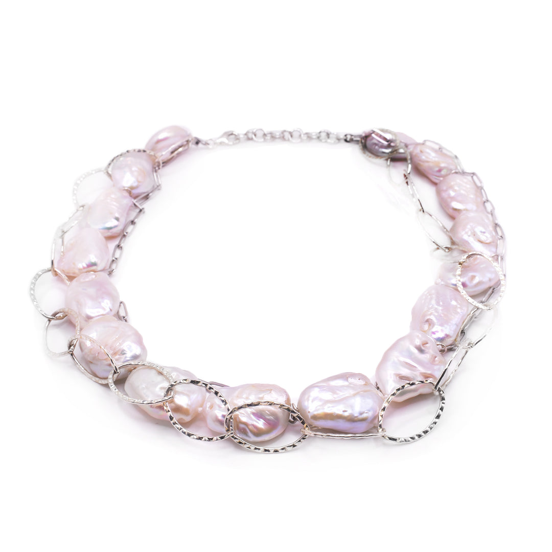 This keshi pearl necklace has large, baroque pearls beaded around the entire piece. The chain is sterling silver and there are sterling silver hoops around the piece accenting the necklace.