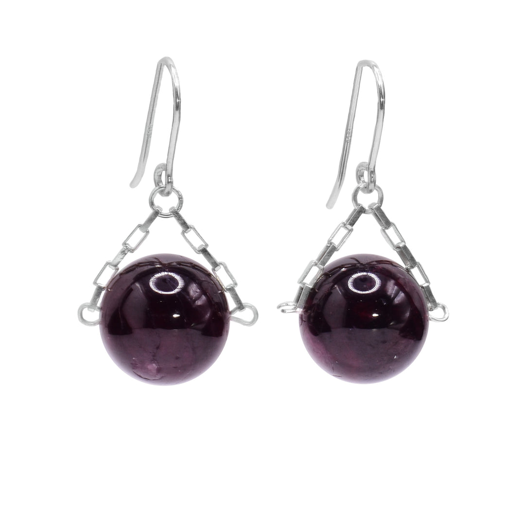 These garnet drop earrings have small, sterling silver chains attached to the hooks and to either side of the garnet hangs. The garnet are large spheres and dangle from the small chains.