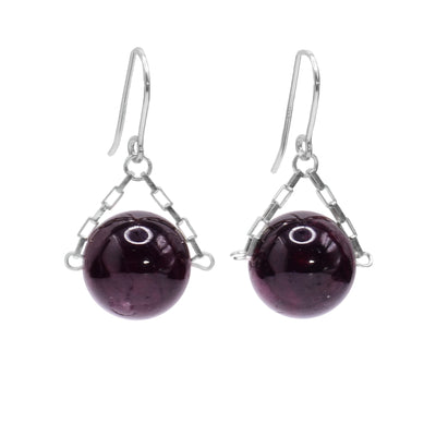 These garnet drop earrings have small, sterling silver chains attached to the hooks and to either side of the garnet hangs. The garnet are large spheres and dangle from the small chains.