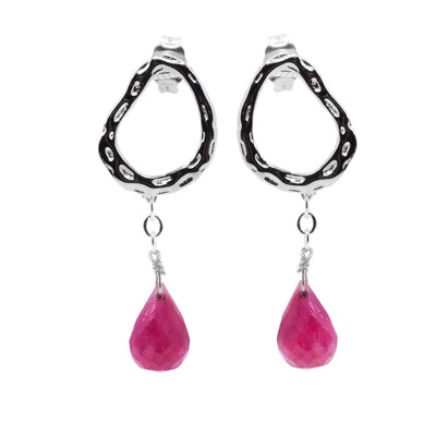These ruby dangle earrings have sterling silver hoops with a dimple pattern made on the surface of them. The hoops are attached to studs and has beautifully cut, teardrop shaped rubies dangling from silver wire below them.