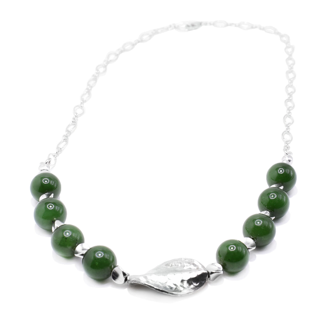 This jade bead necklace has a dainty, sterling silver chain with eight jade beads at the bottom part with a silver leaf charm in the middle of them.