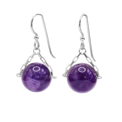 These amethyst drop earrings have small, sterling silver chains attached to the hooks and to either side of the amethyst hangs. The amethyst are large spheres and dangle from the small chains.