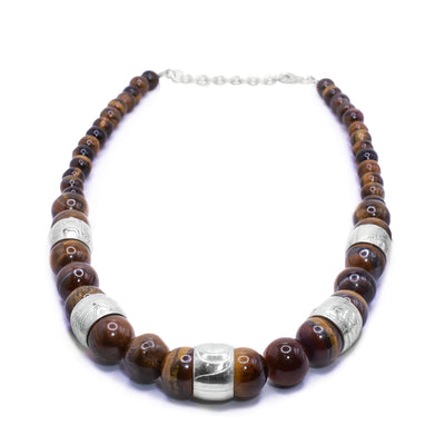 This chunky tiger's eye necklace has sphere shaped gemstone beads that are larger at the bottom portion of the piece and smaller at the tops of it. There are five sterling silver spirit beads that are ditributef through the large beads. The spirit beads have depictions of the Bear, the Orca, the Eagle, the Beaver and the Heron carved into the surface of them.