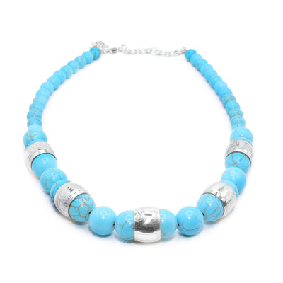 This chunky turquoise necklace has sphere shaped gemstone beads that are larger at the bottom portion of the piece and smaller at the tops of it. There are five sterling silver spirit beads that are distributed through the large beads. The spirit beads have depictions of the Bear, the Orca, the Eagle, the Beaver and the Heron carved into the surface of them.