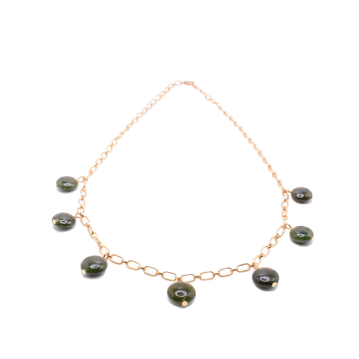 This jade charm necklace has a simple 14K gold filled chain with 7 jade beads at the bottom half of the piece. The jade charms are small, circular and flat.
