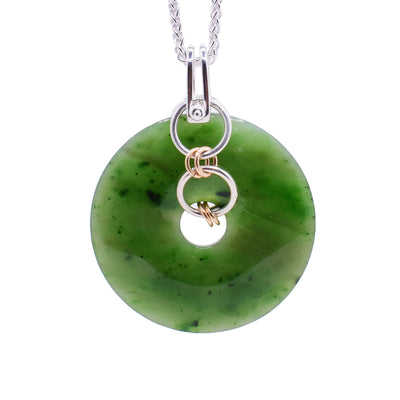 This piece has a large, wide, jade pendant with sterling silver and gold fill hoops linked through it.