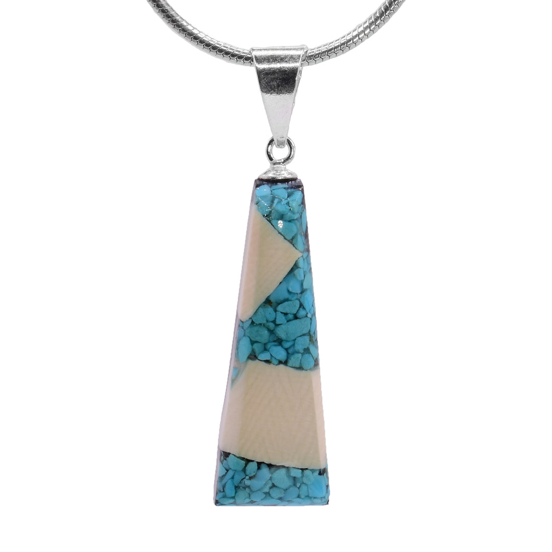 This turquoise pendant is made from fossilized mammoth ivory and turquoise gemstones. Pieces of turquoise and chunks of ivory have been set in resin and has a long, tapered shape..