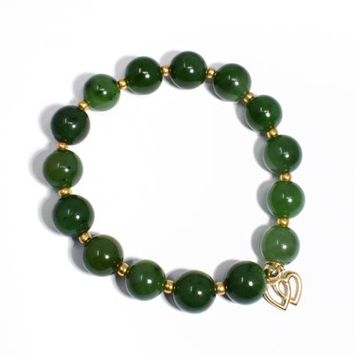 Round, BC jade beads 0.4” in diameter. Small, golden Czech glass beads in between. Adornment featuring two interlocking gold-fill hearts hangs off bracelet.