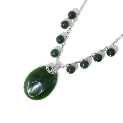 Egg-shaped pendant with oval indent at bottom and silver ring adornments around bail. 8 round BC jade beads hang off chain. All metal is sterling silver.