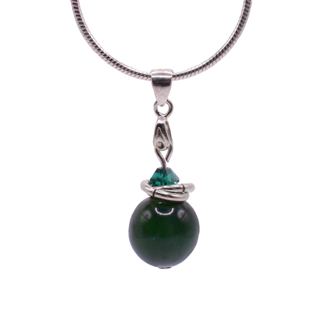 This BC Jade and Crystal Drop Pendant features two sterling silver charm wrapped around a green crystal and underneath is a BC Jade sphere. The elements are securely connected with sterling silver, creating a simple and elegant design.