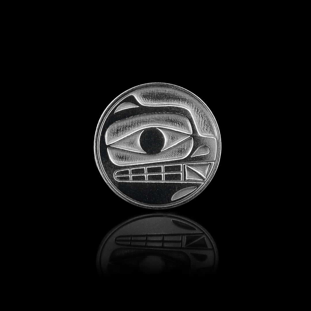 This sterling silver golf ball marker is perfectly circular and features a hand-carved bear design at its center.