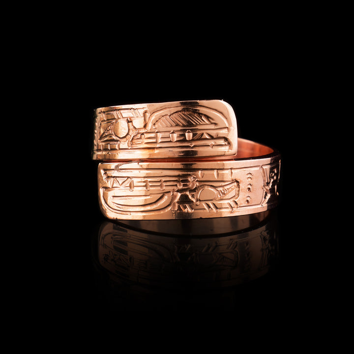 This copper wrap around ring has a single band that wraps around the finger twice. There is a depiction of the Bear head at one end of the band and another on the other end. The depictions are done in a side profile with hatching design in the background of the scene.