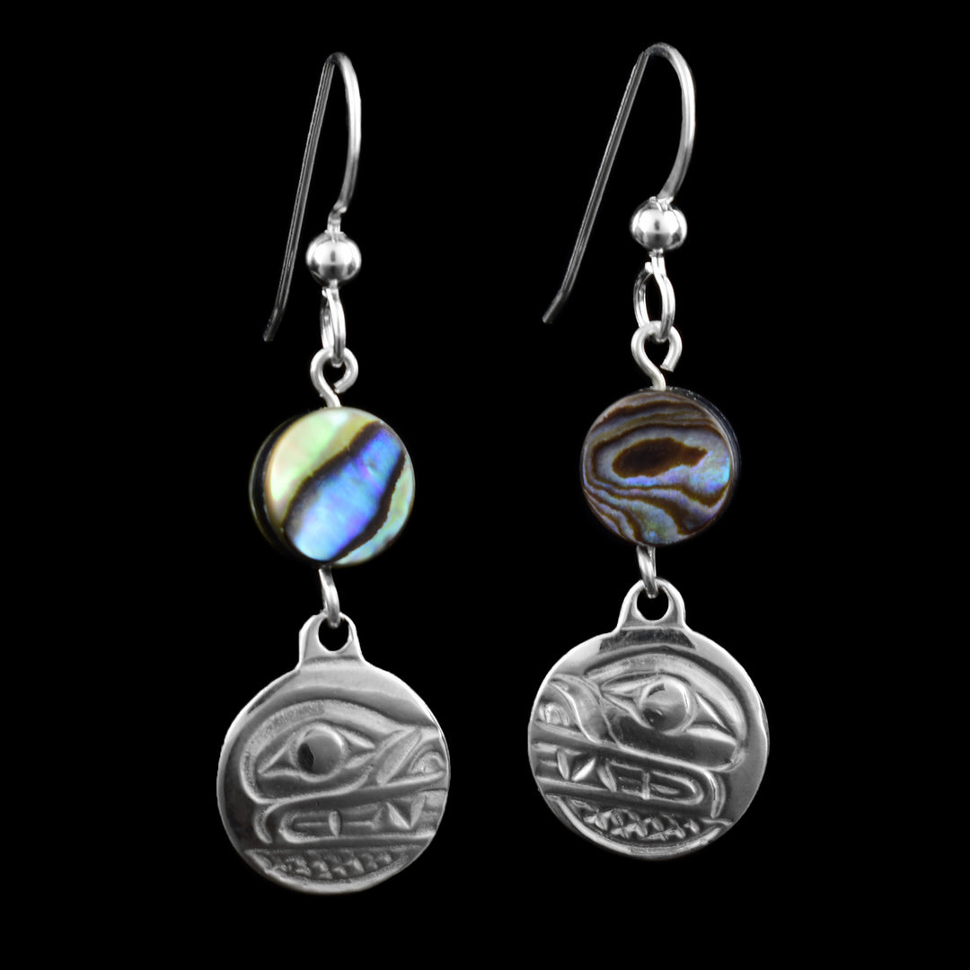 These dangle bear earrings feature a carved bear design engraved in round sterling silver. On top of the earring is a circular abalone shell bead, displaying natural swirls of colourful blues, greens, and purples that shimmer when caught in the light. Finished with classic French hooks.