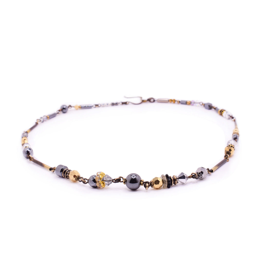 This unique Honica mixed media necklace features hematite, gold pyrite, and crystals. Handcrafted with an antique bronze finish and a secure hook clasp.