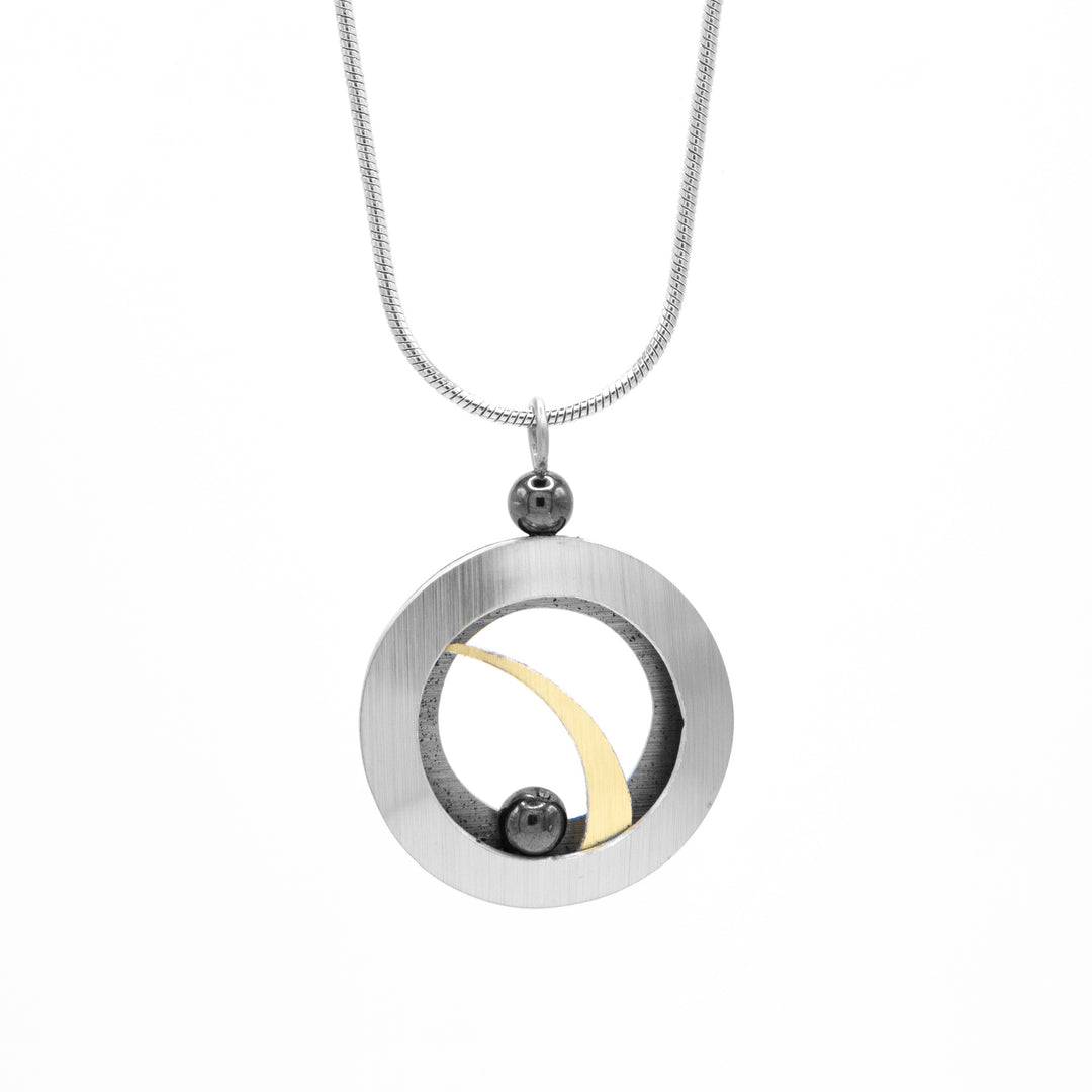 Brushed and anodized round aluminum open pendant with two hematite beads. One bead on top and one inside on bottom. Stainless steel snake chain included. By JR Franco.