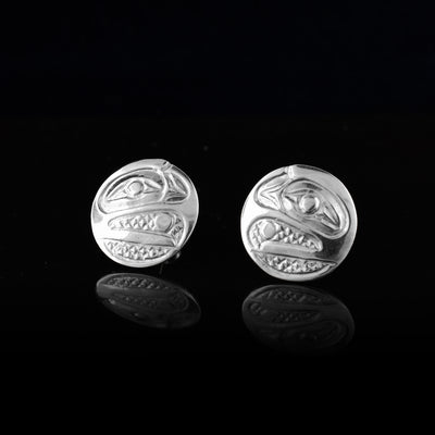 These Circle Stud Earrings are made from sterling silver and have the head of the Raven depicted at a side profile. The eye is large and at the top corner and its beak curves down, is open and is holding a pearl between it. There are cross hatching designs in the background of the portrait.