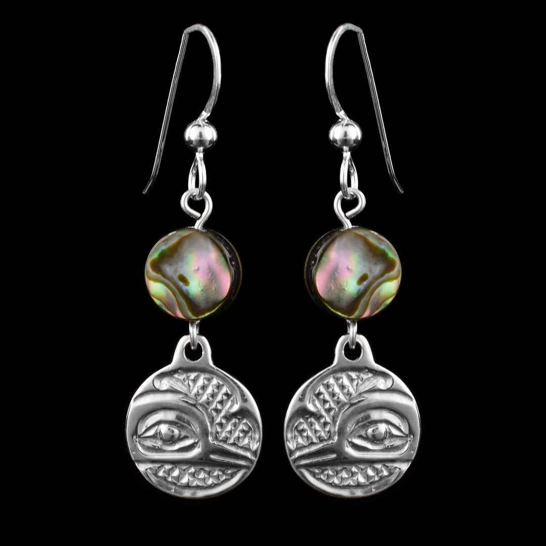 These dangling pearl earrings silver have small, circle hangs made from sterling silver. Below the hooks is a single, round abalone shell charm with the hangs dangling from them. On the hangs, the head of the Hummingbird is shown at a side profile with its narrow beak and eye detailed. There are cross hatching designs in the background of the portrait.