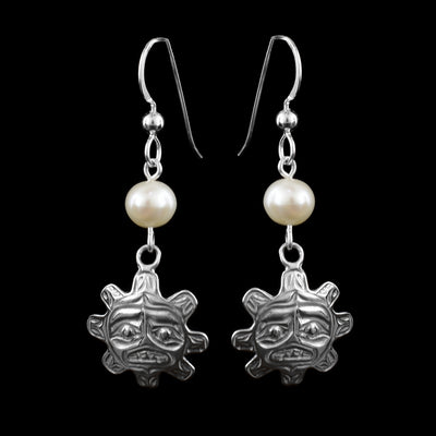 These sterling silver pearl drop earrings has white, freshwater pearls dangling from the long hooks. The hangs are round and have knobs extending from it imitating sun rays. The hangs dangle from the pearls and have features of the face of the sun cast into them including the eyebrows, eyes, and mouth.