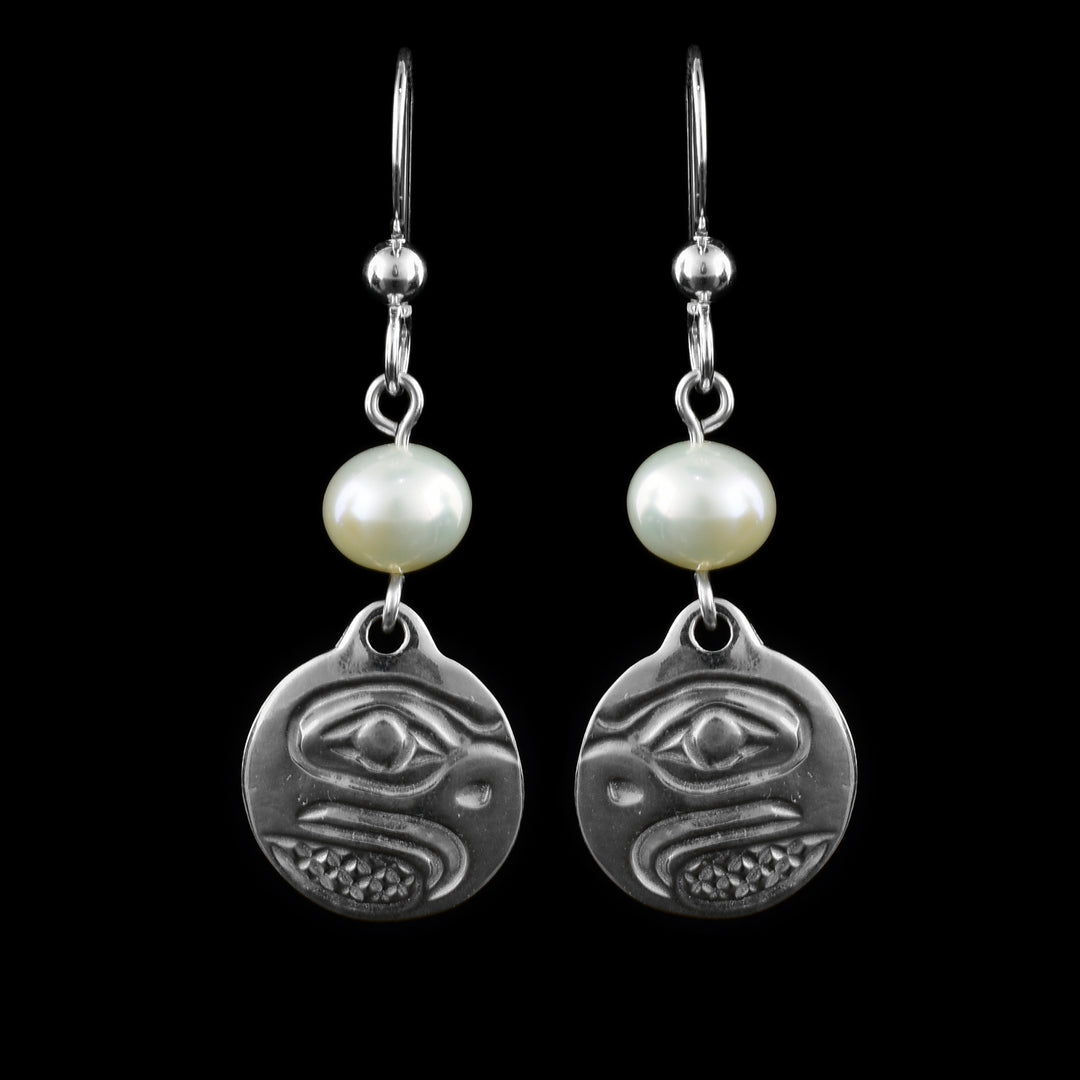 These dangling pearl earrings silver have small, circle hangs made from sterling silver. Below the hooks is a single, white pearl with the hangs dangling from them. On the hangs, the head of the Eagle is shown at a side profile with its beak (curved at the end), eyes and nose detailed. There are cross hatching designs in the background of the portrait.