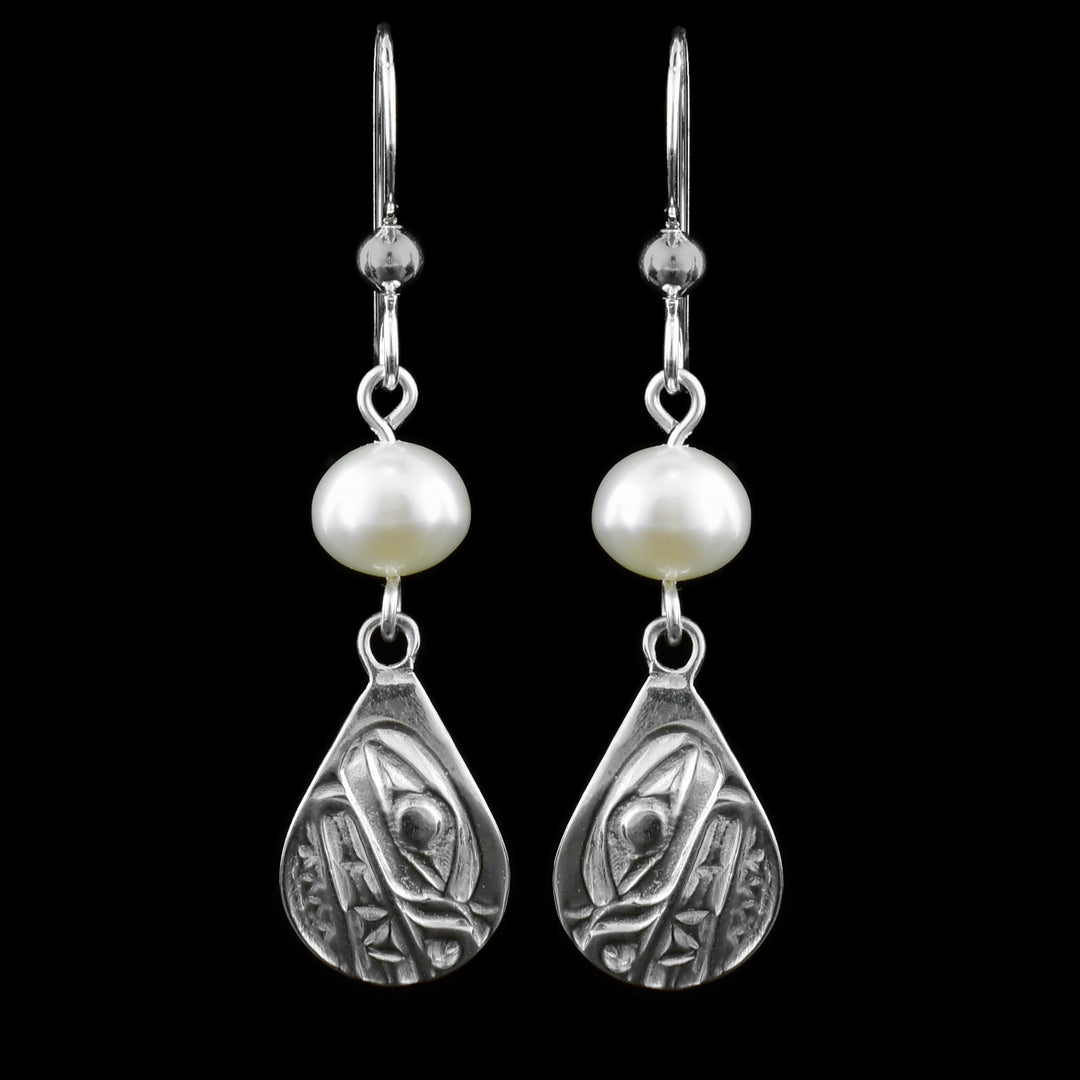 These dangling teardrop earrings have teardrop shaped hangs cast from sterling silver. There is a single, white pearl below the hooks and above the hangs. The head of the Bear is cast into the hangs and its snout is facing down. The mouth is large and takes up most of the hangs. There are cross hatching designs in the background of the portrait.