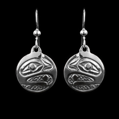 These Raven earrings have small, sterling silver hangs attached to hooks. The head of the Raven carved at a side profile into the hangs. Its eyes and beak are visible and there are cross hatching designs in the background of the portrait.