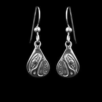 These dangling teardrop earrings have teardrop shaped hangs cast from sterling silver. The head of the Eagle is cast into the hangs and its beak is facing down. The beak is curved at the end and takes up most of the hangs. There are cross hatching designs in the background of the portrait.