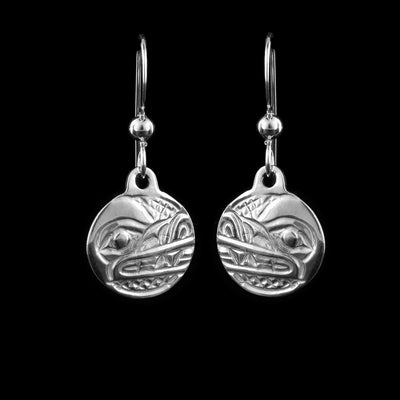 These Wolf earrings have small, sterling silver hangs attached to hooks. The head of the Wolf carved at a side profile into the hangs. Its teeth are visible and there are cross hatching designs in the background of the portrait.