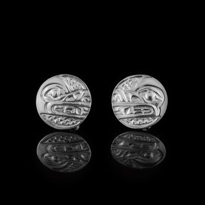 These Wolf stud earrings are made from sterling silver and have circle shaped studs. The head of the Wolf is depicted in a side profile on the studs. His mouth and eye are detailed with cross hatching patterns in the background.