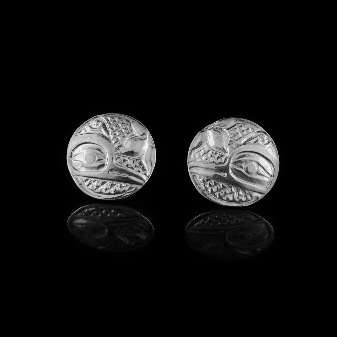 These Hummingbird stud earrings are made from sterling silver and have circle shaped studs. The head of the Humming is depicted in a side profile on the studs. His beak and eye are detailed with cross hatching patterns in the background. There are flower petals in the corner in front of the Hummingbird head.