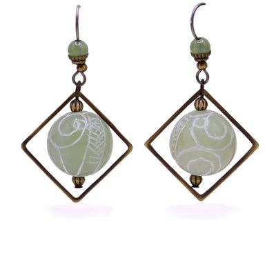 Dangle earrings made of handworked brass, carved jade and jade. Titanium hooks. By Honica.