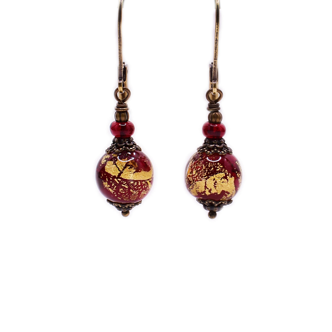 Brass dangle earrings featuring red and gold handmade lampworked glass beads and clear red glass beads.