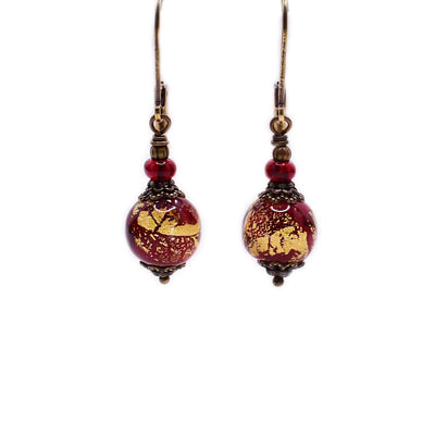 Brass dangle earrings featuring red and gold handmade lampworked glass beads and clear red glass beads.
