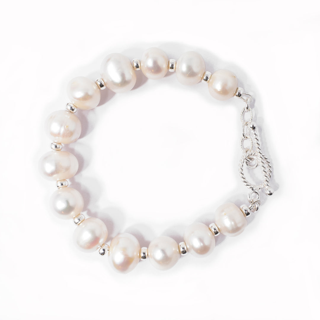 White, unevenly sized freshwater pearls with silver beads in between. Toggle clasp with rope pattern on back. Metal is sterling silver.