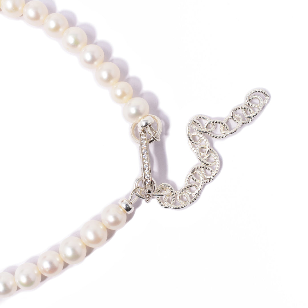 Cream-coloured pearls end at clasp. Cubic zirconia in clasp. Silver extension chain. Metal is sterling silver.