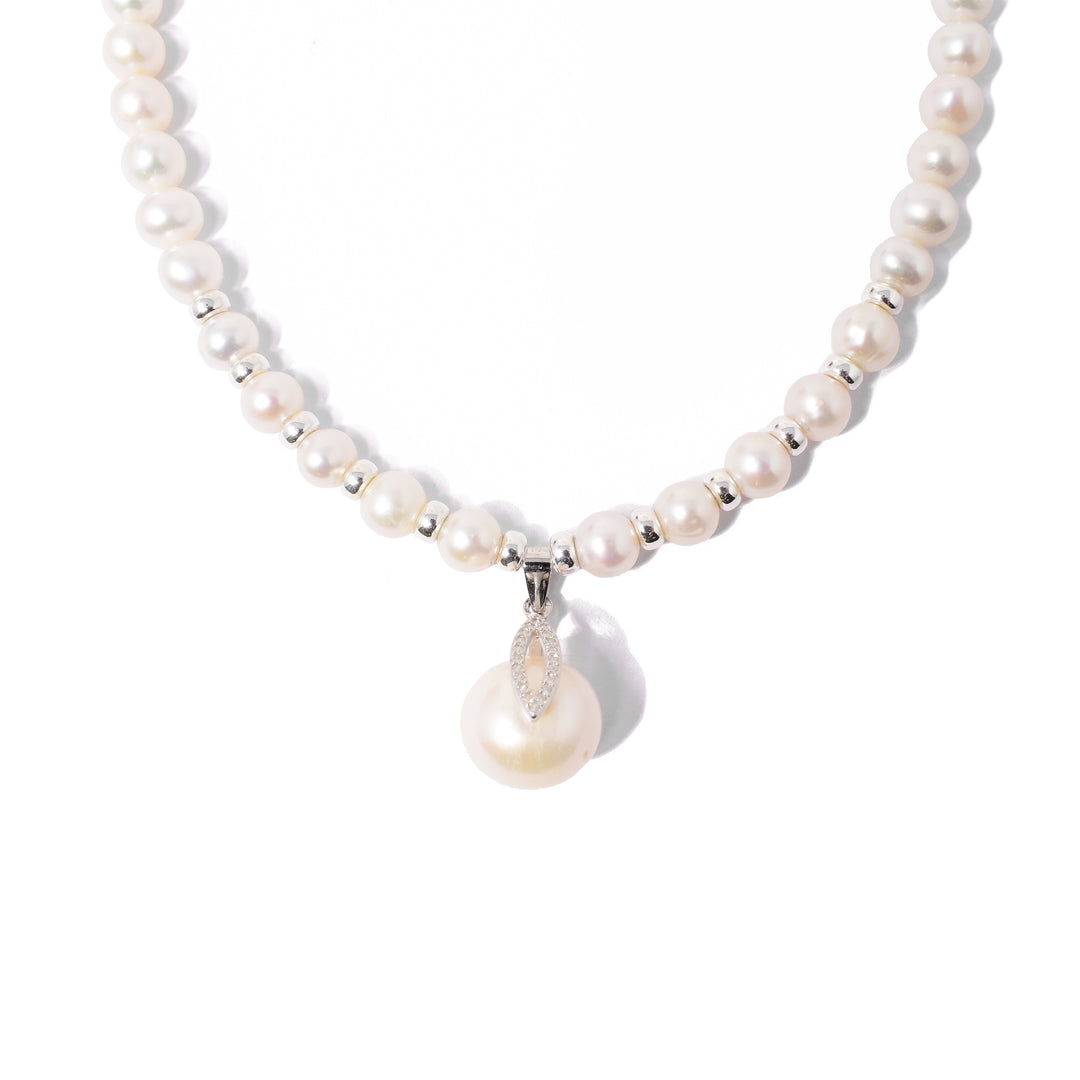 Uneven, cream-coloured pearls with silver beads between foremost pearls. Larger, pearl pendant with cubic zirconia in bail. Metal is sterling silver.