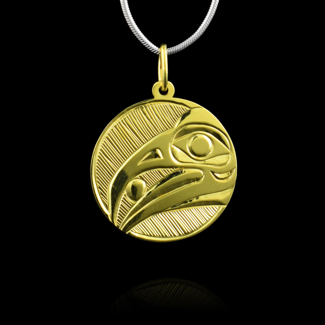 This circular pendant is made with 10k Gold and the legend of the Raven is carved into the surface holding a pearl in its mouth.