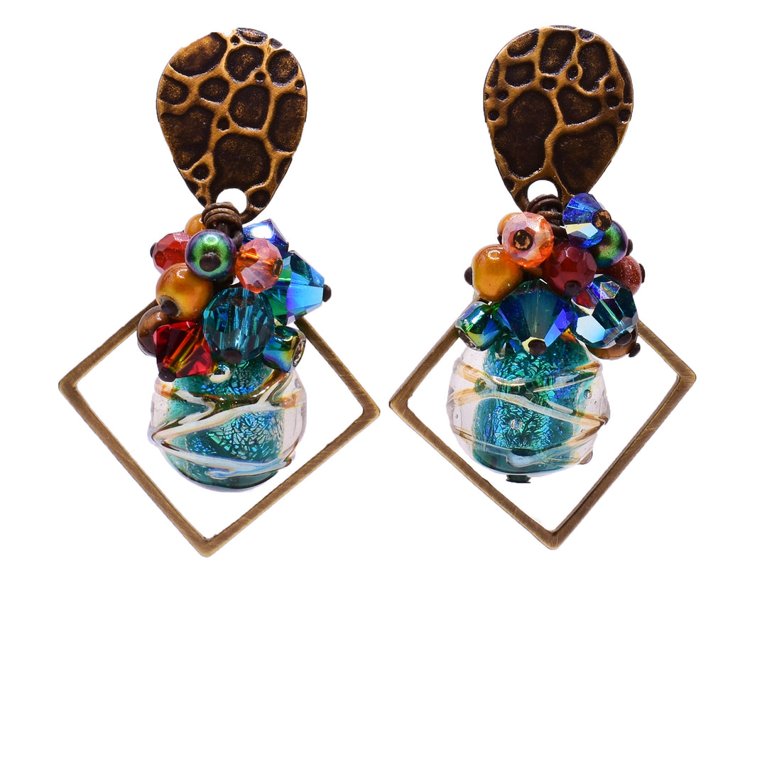Dangle earrings made of carnelian agate, Swarovski crystal, mother of pearl, handworked brass, handmade art glass, amber, goldstone, glass and tiger's eye. Titanium posts. By Honica.