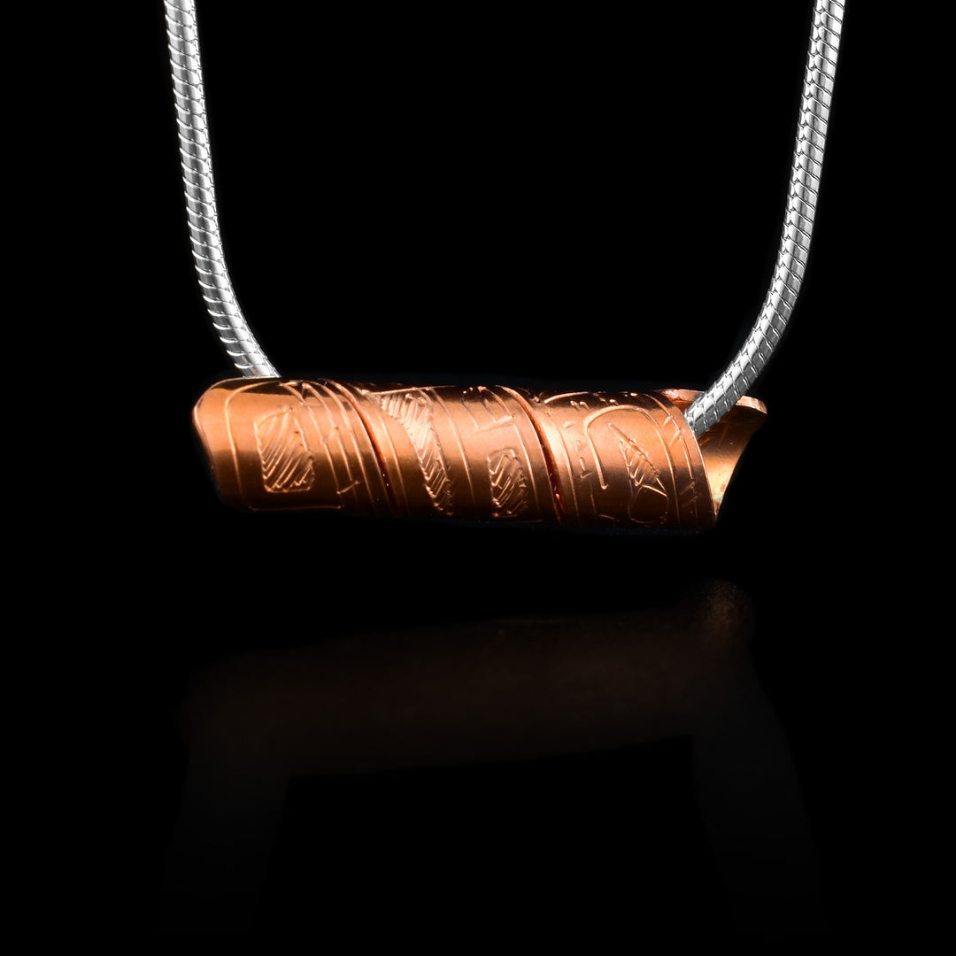 This spiral cylinder pendant is made from a single, copper band that has been twisted into a cylinder. There is depiction of the Bear legend carved into the surface of the band so it appears on the outside of the cylinder. It is shown at a side profile with its head, eye and mouth at one end on the rest of its body behind it.
