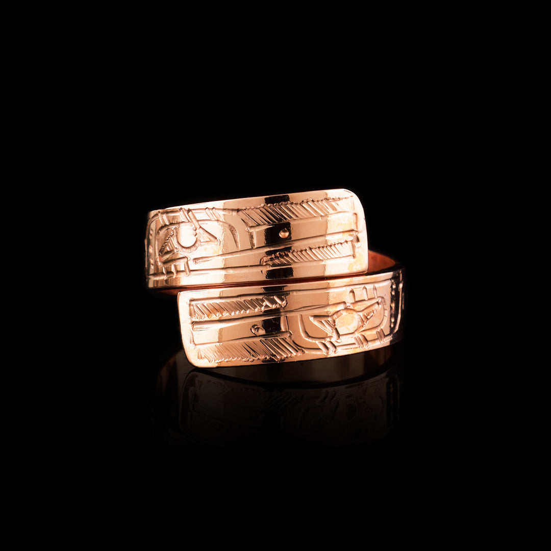 This copper wrap around ring has a single band that wraps around the finger twice. There is a depiction of the Hummingbird head at one end of the band and another on the other end. The depictions are done in a side profile. There are feather designs behind the back of its head.