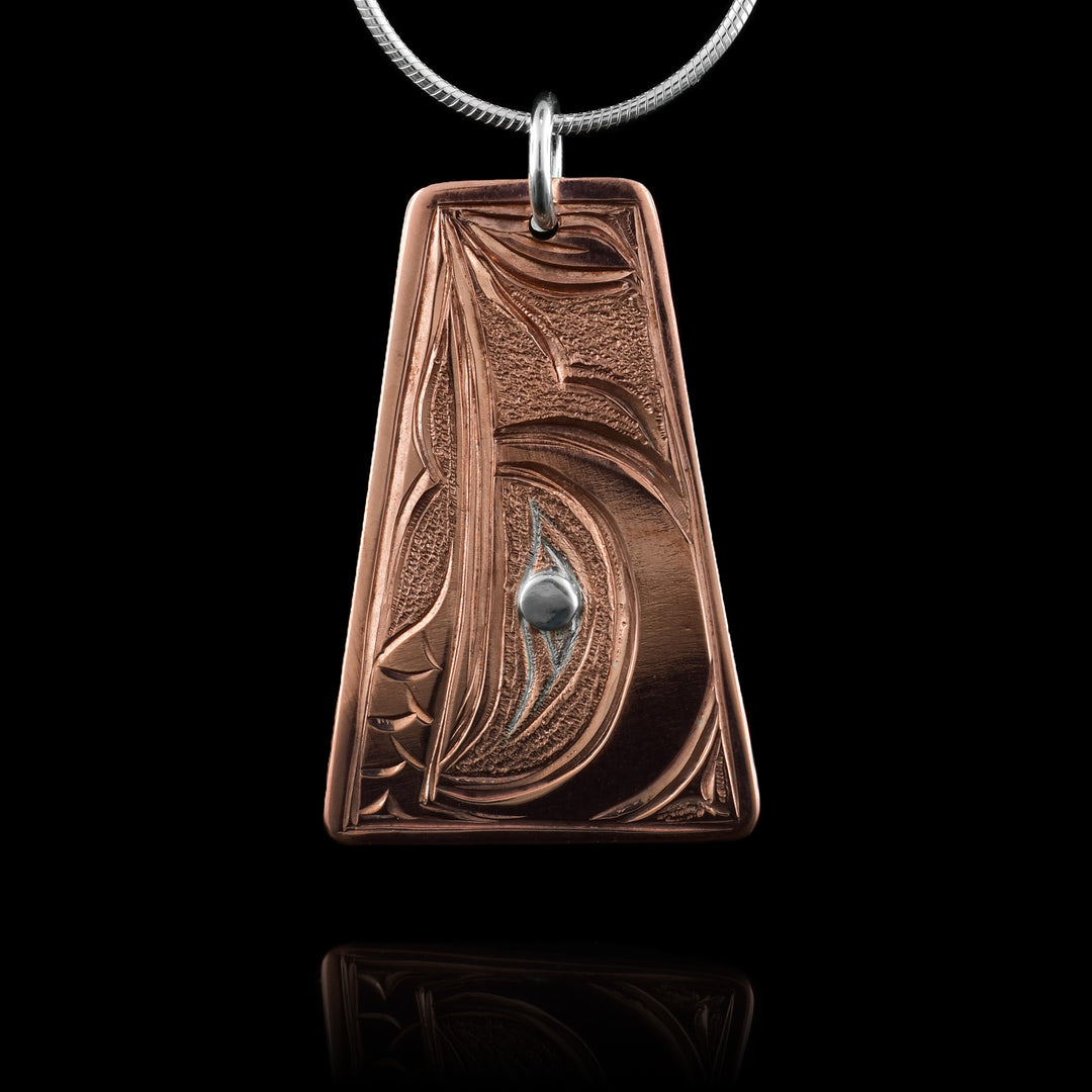 This handcrafted copper Hummingbird pendant features a beautifully carved design. The Hummingbird’s head is detailed with flowing lines and textures, symbolizing joy and connection. A polished silver inlay forms the eye.