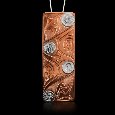A rectangular copper pendant that depicts abstract Orca and Eagle heads in silver.  