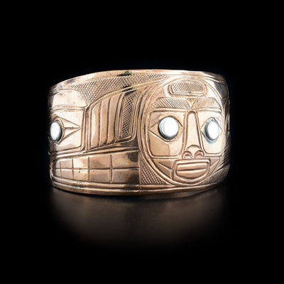 Depicts moon in center and wolf on right, sterling silver in eyes. Cross-hatching background. Tapered ends. Hand-carved by Heiltsuk artist Reg Gladstone.